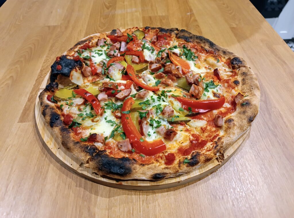 Zdjęcie przedstawiające upieczoną pizzę z piekarnika na prefermencie poolish.